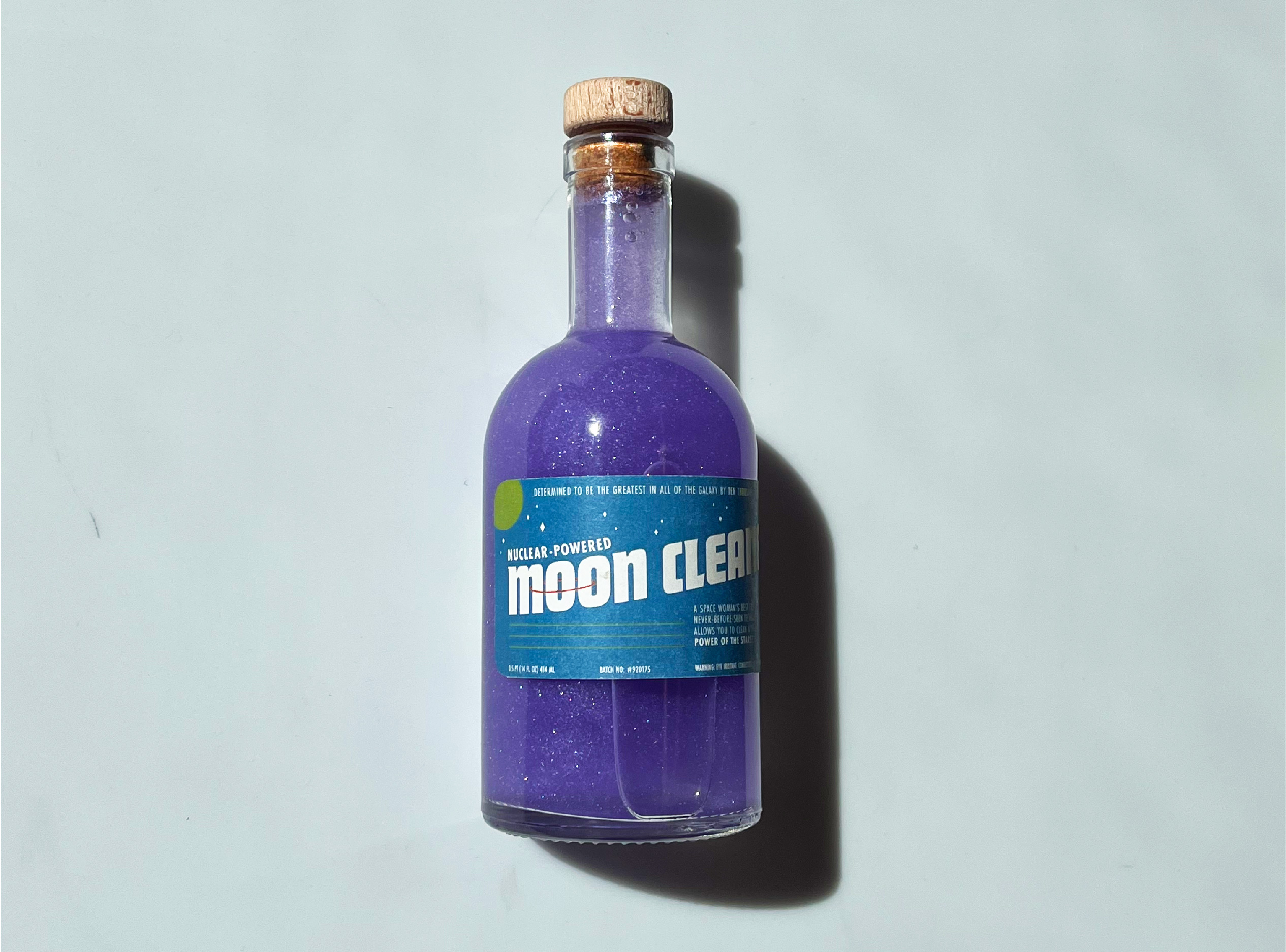Image of the Moon Cleaner product, which is a space-age style bottle with a cork top and purple glittery liquid inside.